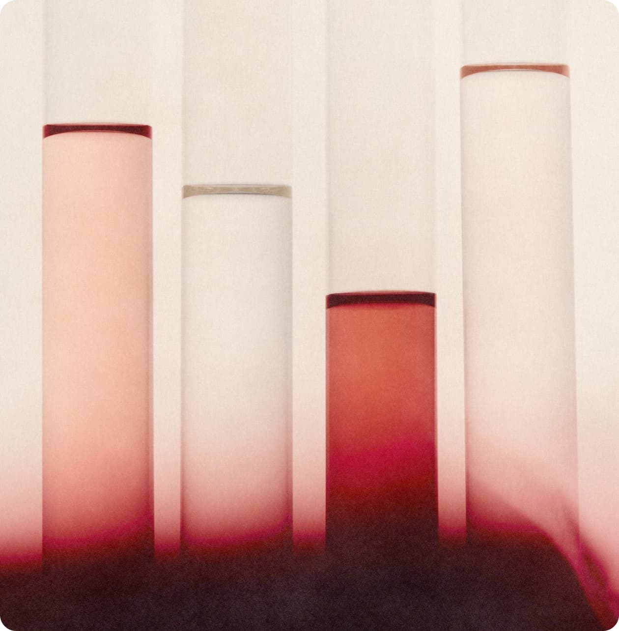 Four glass cylinders shading from cream to deep red