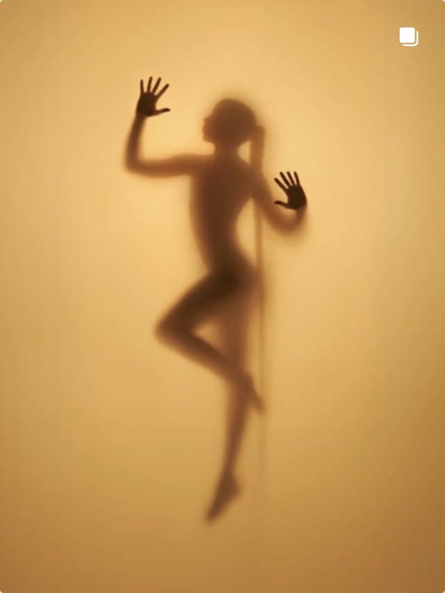 A figure in silhouette behind warm frosted glass
